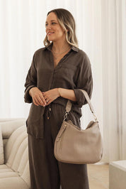 A model wearing the Nadia Shoulder Bag in colour Malt, from the front, showing the whole outfit