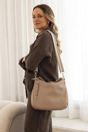A model wearing the Nadia Shoulder Bag in colour Malt, from the front, showing the whole outfit