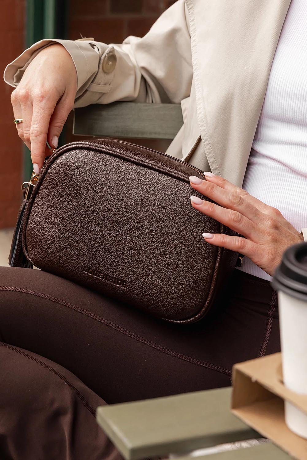 A model wearing the Jacinta Gia Crossbody Bag in colour Chocolate, from the front, showing the whole outfit