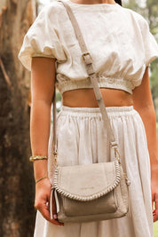 A model wearing the Shania Crossbody Bag in colour Stone, from the front, showing the whole outfit