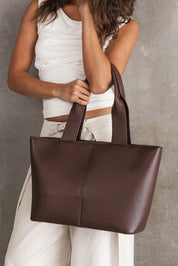 A model wearing the Henley Tote Bag in colour Chocolate, from the front, showing the whole outfit