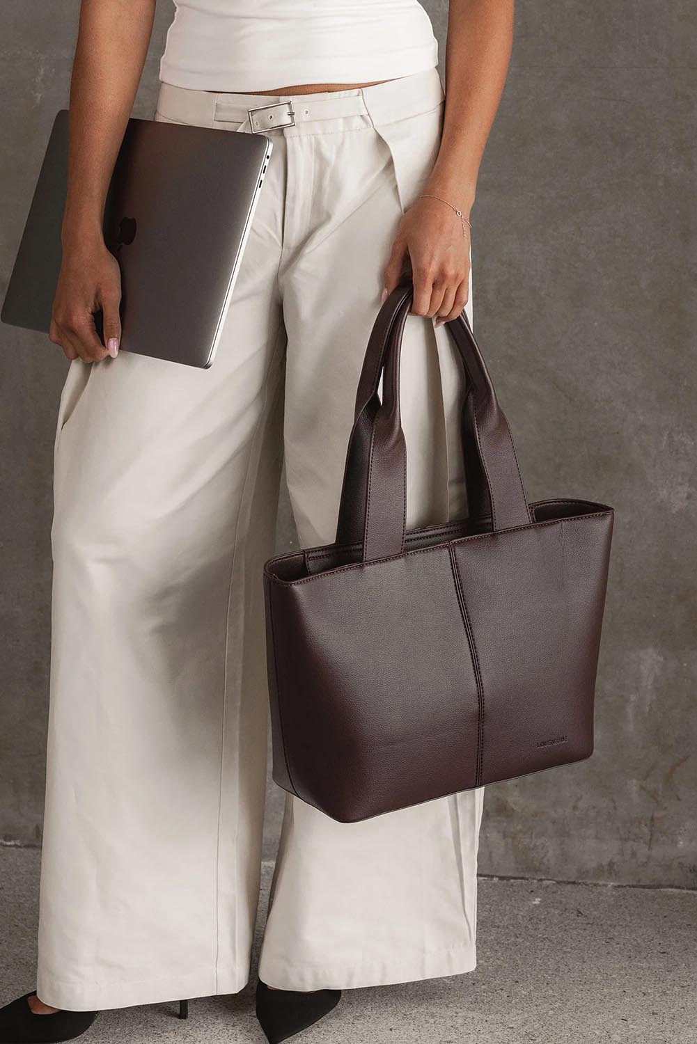 A model wearing the Henley Tote Bag in colour Chocolate, from the front, showing the whole outfit