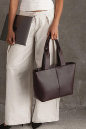 A model wearing the Henley Tote Bag in colour Chocolate, from the front, showing the whole outfit