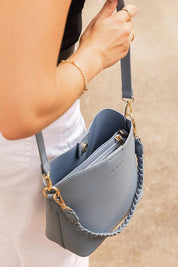 A model wearing the Soho Crossbody Bag in colour Dustyblue (Blue), from the front, showing the whole outfit
