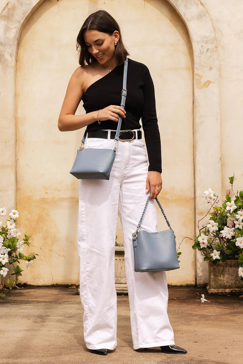 A model wearing the Soho Crossbody Bag in colour Dustyblue (Blue), from the front, showing the whole outfit