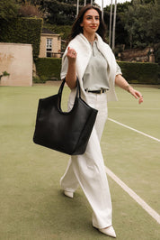 A model wearing the Alexandra Tote Bag in colour Black (Black), from the front, showing the whole outfit