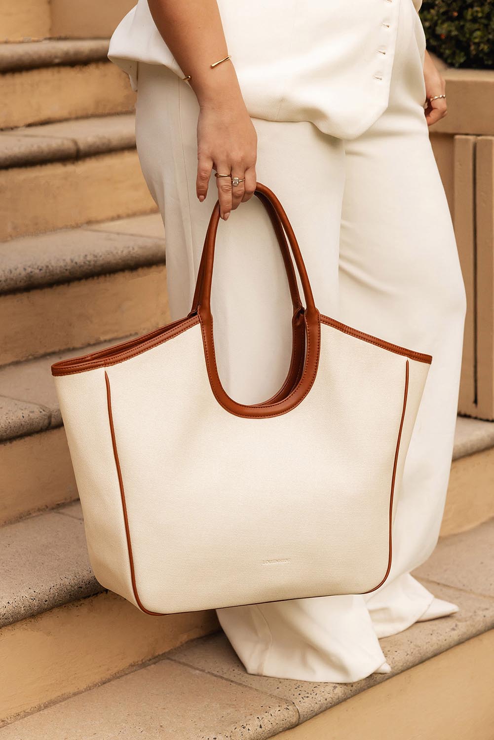 A model wearing the Alexandra Tote Bag in colour Natcanvas, from the front, showing the whole outfit