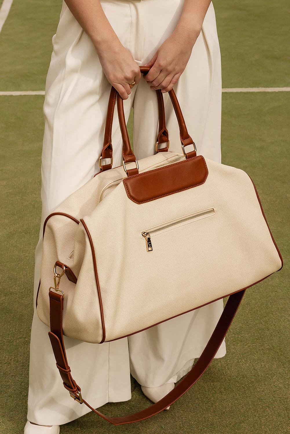 A model wearing the Taylor Travel Bag in colour Canvastan, from the front, showing the whole outfit