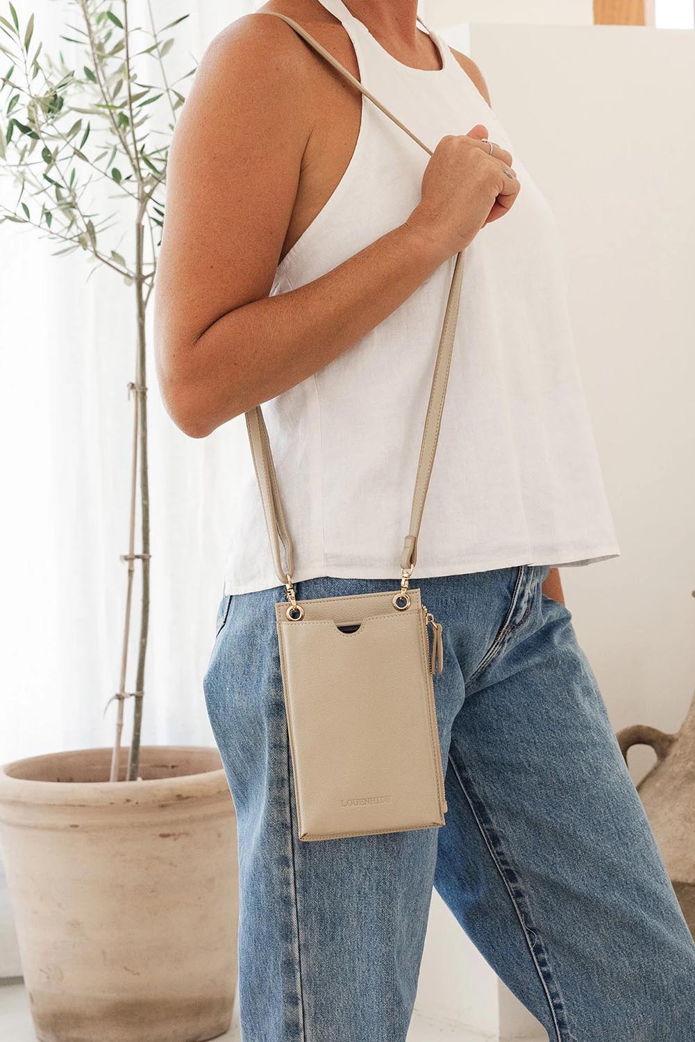 A model wearing the Suki Phone Bag in colour Almond, from the front, showing the whole outfit