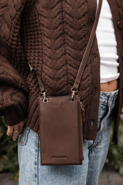 A model wearing the Suki Phone Bag in colour Chocolate, from the front, showing the whole outfit