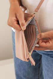 A model wearing the Suki Phone Bag in colour Dustypink (Pink), from the front, showing the whole outfit