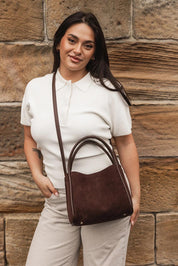A model wearing the Steffie Suedette Mini Tote Bag in colour Chocolate, from the front, showing the whole outfit