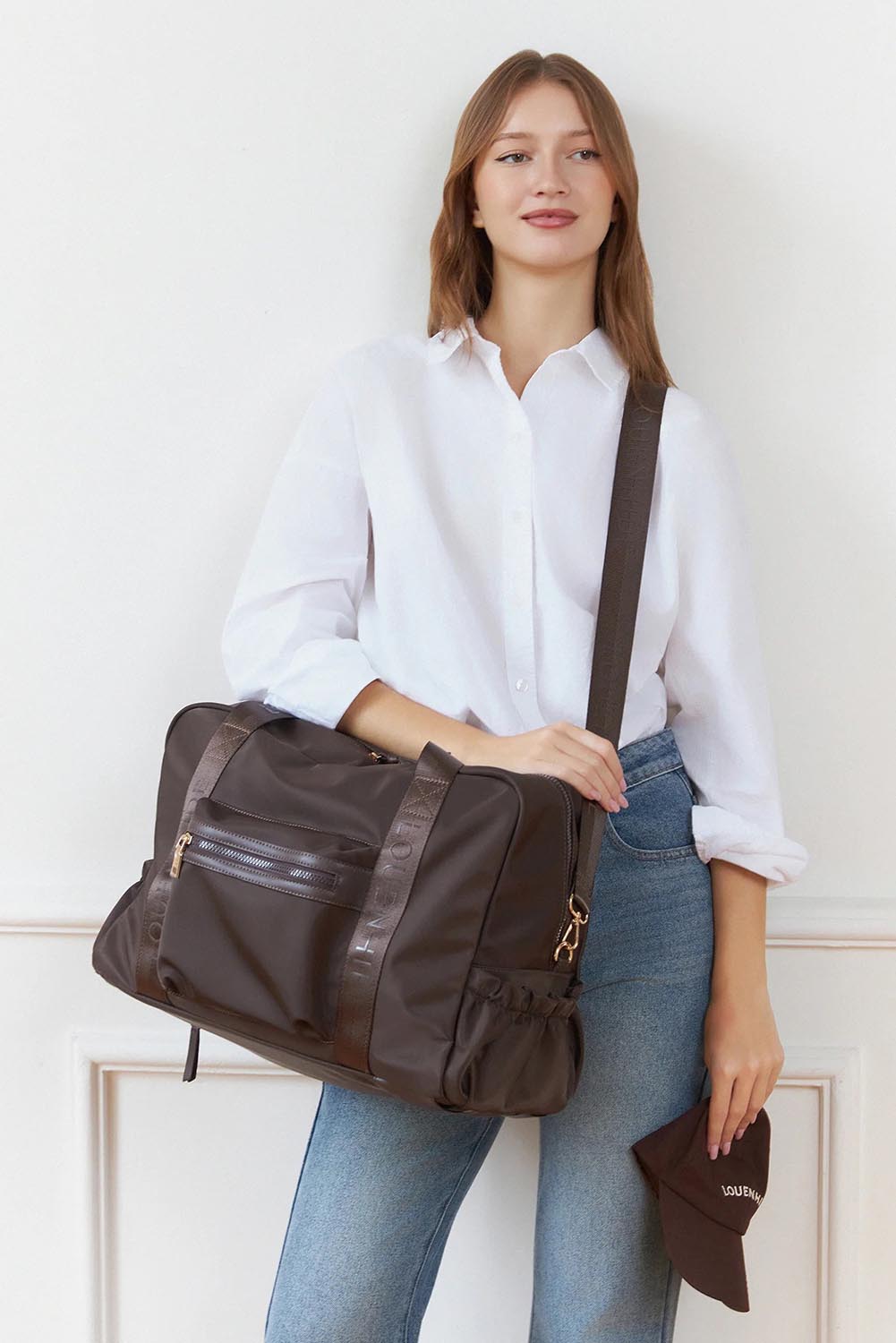 Model Genericm wearing size sample of the Jenn Nylon Travel Bag - Chocolate in colour Chocolate, in a cropped view