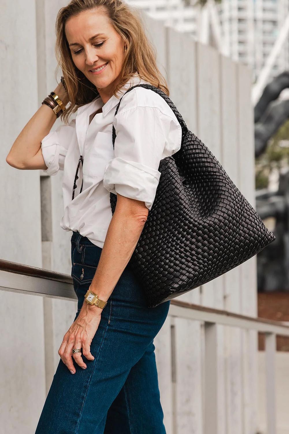 A model wearing the Gabby Woven Shoulder Bag in colour Black (Black), from the front, showing the whole outfit
