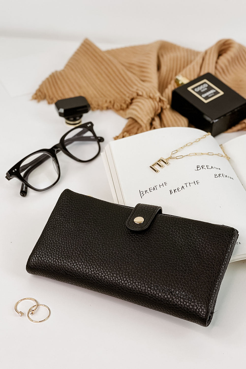 A model wearing the Stella Fold Over Wallet in colour Black (Black), from the front, showing the whole outfit