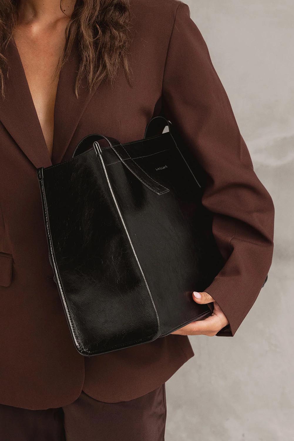 A model wearing the Riley Tote Bag in colour Blackpaten (Black), from the front, showing the whole outfit