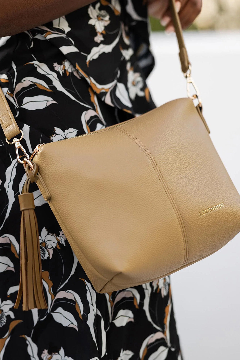 A model wearing the Kasey Crossbody Bag in colour Latte, from the front, cropped image