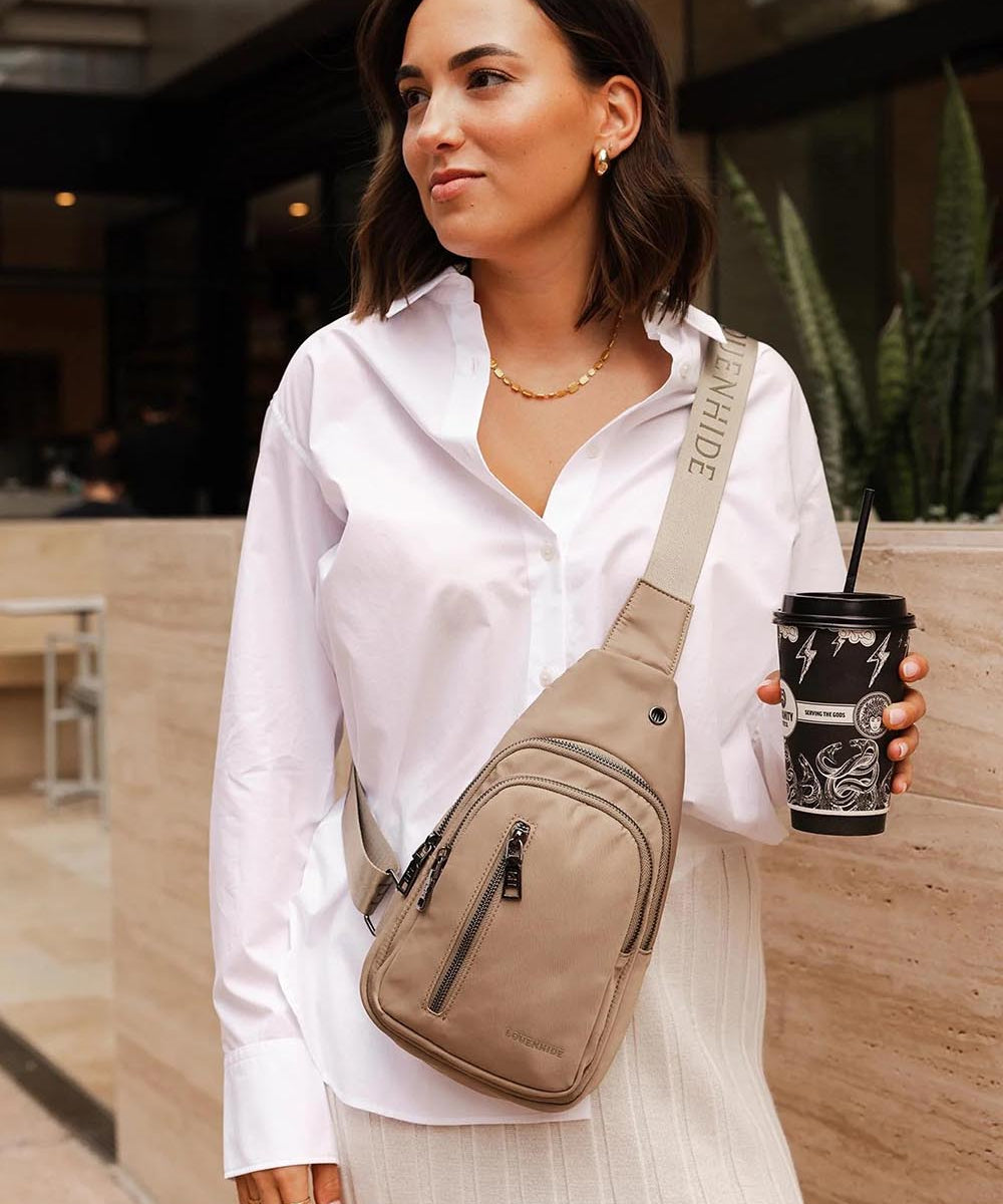 A model wearing the Boyd Nylon Sling Bag in colour Beige, from the front, showing the whole outfit