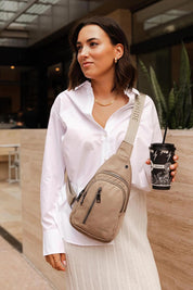 A model wearing the Boyd Nylon Sling Bag in colour Beige, from the front, showing the whole outfit