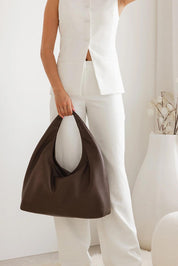 A model wearing the Monaco Shoulder Bag in colour Chocolate, from the front, showing the whole outfit