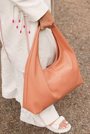 A model wearing the Monaco Shoulder Bag in colour Clay, from the front, showing the whole outfit