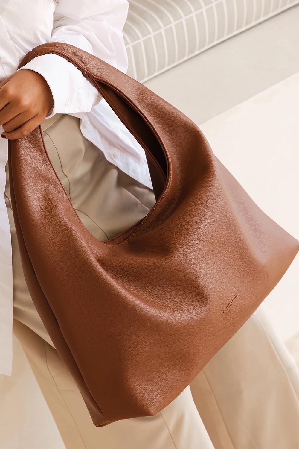A model wearing the Monaco Shoulder Bag in colour Tan, from the front, showing the whole outfit