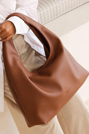 A model wearing the Monaco Shoulder Bag in colour Tan, from the front, showing the whole outfit