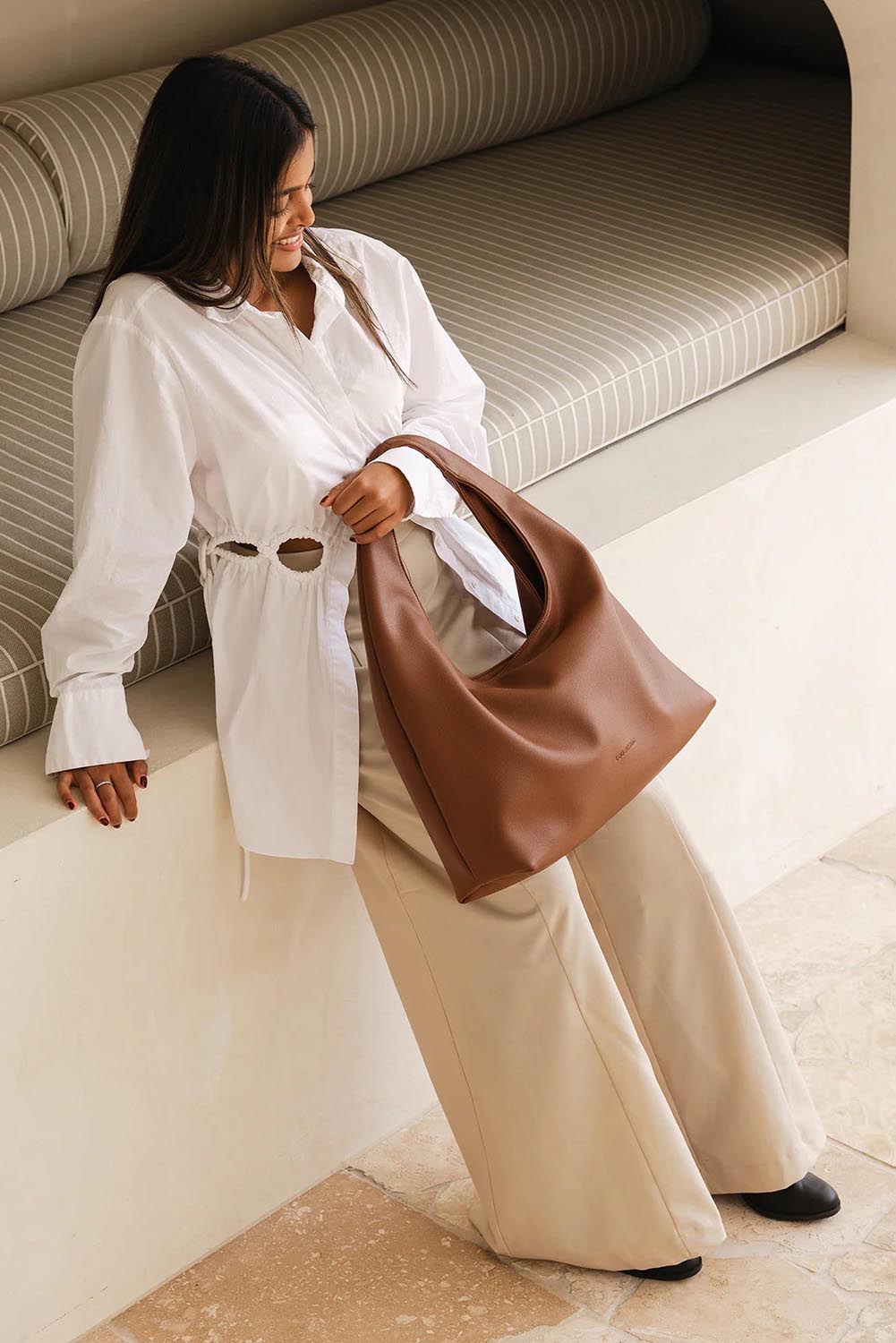 A model wearing the Monaco Shoulder Bag in colour Tan, from the front, showing the whole outfit