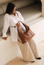 A model wearing the Monaco Shoulder Bag in colour Tan, from the front, showing the whole outfit