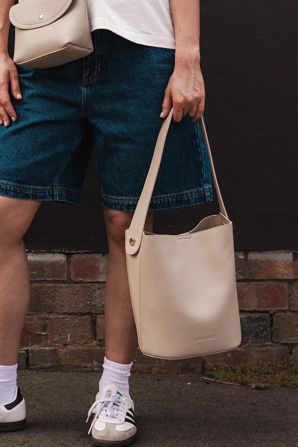 A model wearing the Miranda Bucket Bag in colour Almond, from the front, showing the whole outfit