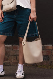 A model wearing the Miranda Bucket Bag in colour Almond, from the front, showing the whole outfit