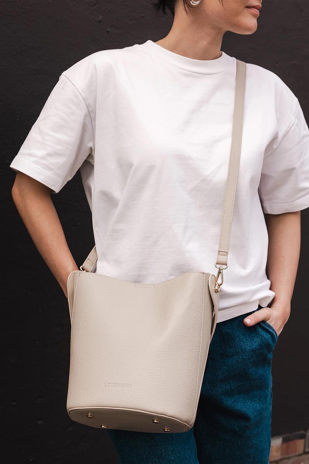 A model wearing the Miranda Bucket Bag in colour Almond, from the front, showing the whole outfit