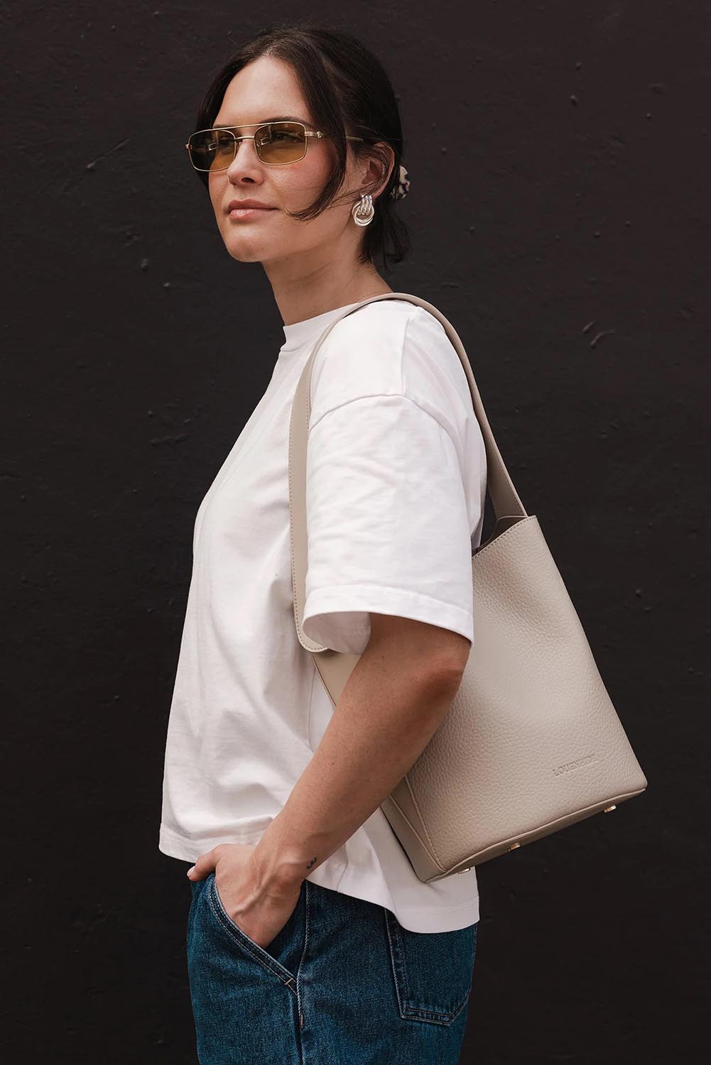 A model wearing the Miranda Bucket Bag in colour Almond, from the front, showing the whole outfit
