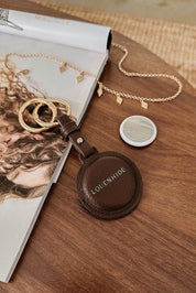 A model wearing the Opal Airtag Holder in colour Chocolate, from the front, showing the whole outfit