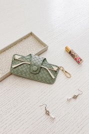 A model wearing the Woven Skittle Glasses Case in colour Sagegreen (Green), from the front, showing the whole outfit