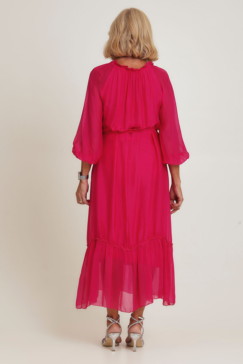 Model Sandy wearing the Long Sleeve Silk Frill Tied Neck Dress in colour Raspberry (Pink), from the back