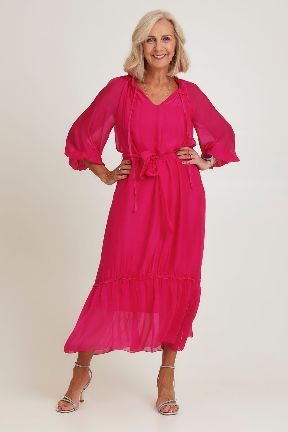 Model Sandy wearing the Long Sleeve Silk Frill Tied Neck Dress in colour Raspberry (Pink), from the front, showing the whole outfit