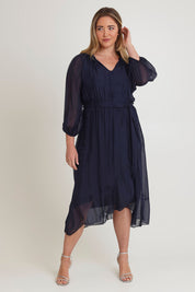 Model Chanel wearing the Long Sleeve Silk Frill Tied Neck Knee Length Dress in colour Navy (Blue), from the front, showing the whole outfit
