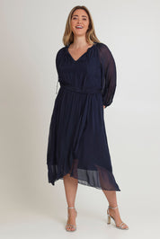 Model Chanel wearing the Long Sleeve Silk Frill Tied Neck Knee Length Dress in colour Navy (Blue), from the front, showing the whole outfit