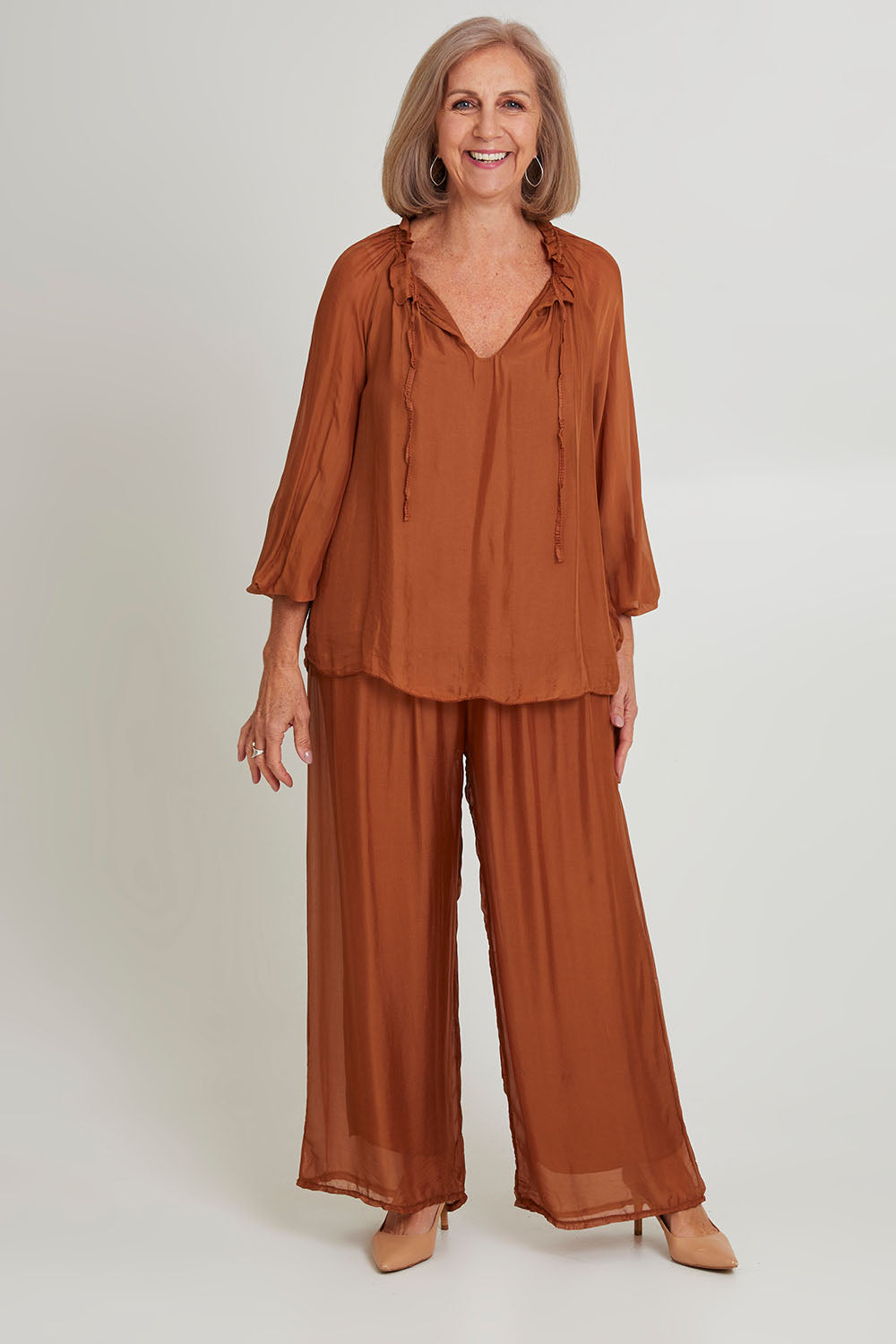 Model Sandy wearing the Silk Pant in colour Goldbrown (Metallics), from the front, showing the whole outfit