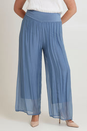 Model Chanel wearing the Silk Pant in colour Jeans (Blue), from the front, cropped image