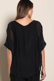 Model Maddiec wearing size 10 of the Silk Blend Three Layer Raw Edge Top - Black in colour Black, from the back