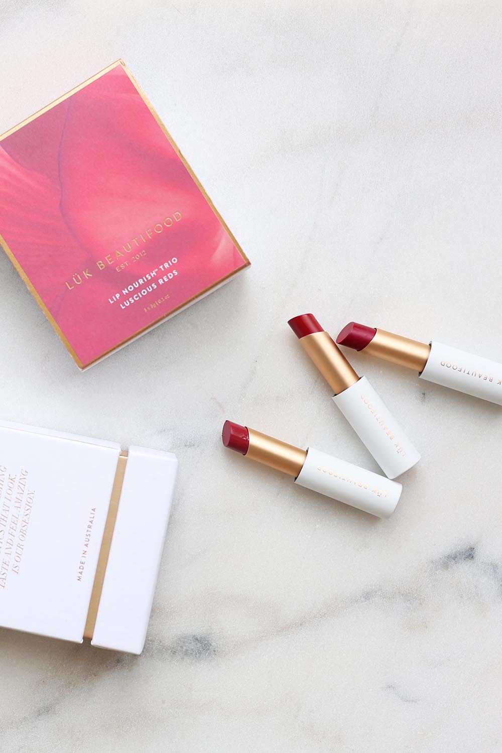 A model wearing the Lip Nourish Trio in colour Reds (Red), from the front, showing the whole outfit
