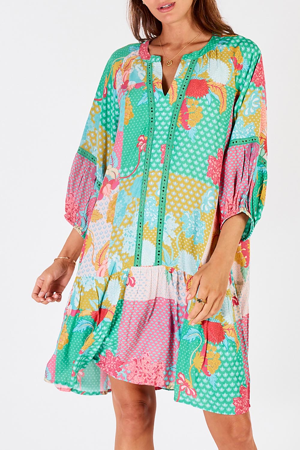 A model wearing the Camargue Dress in colour Lagoon (Green), from the front, cropped image