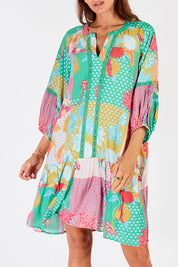 A model wearing the Camargue Dress in colour Lagoon (Green), from the front, cropped image
