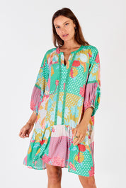 A model wearing the Camargue Dress in colour Lagoon (Green), from the front, cropped image