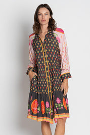 A model wearing the Grenadine Dress in colour Truffle, from the front, cropped image