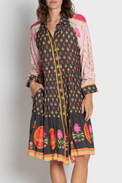 A model wearing the Grenadine Dress in colour Truffle, from the front, cropped image