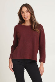 Model Madeline wearing size S of the Moriko Sweater in colour Spice, from the front, cropped image