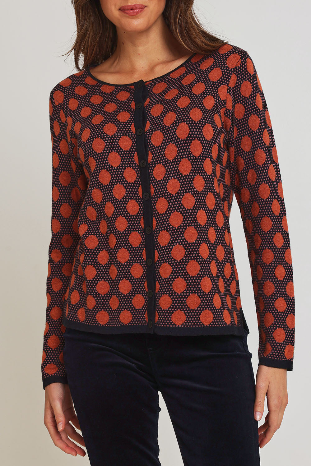 Model Madeline wearing size S of the Sne Organic Cotton Cardigan in colour Rust, from the front, cropped image